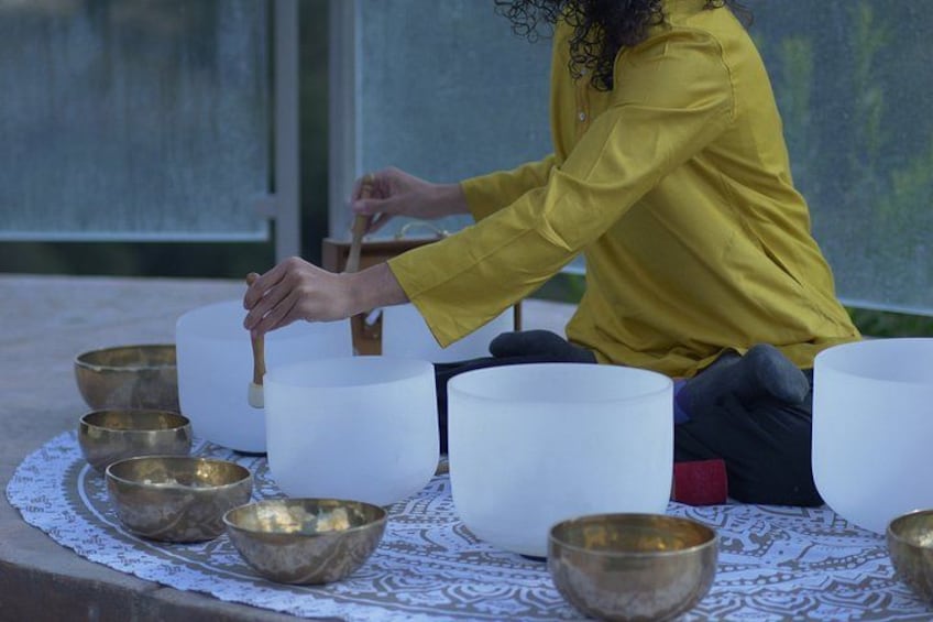 A person in a yellow shirt sitting on a white cloth, playing a large white drum. 2