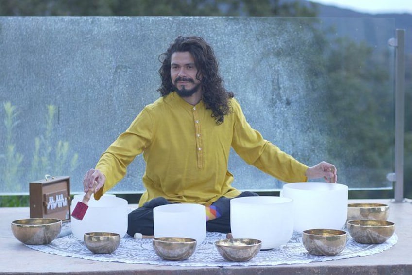 A person sitting cross-legged on a mat surrounded by bowls and a white object. 1