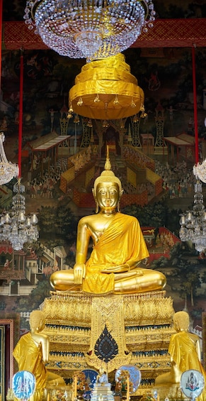 A golden Buddha statue in a temple with intricate architecture and hanging chandeliers. 1