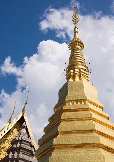 A golden stupa with intricate carvings against a blue sky. 5