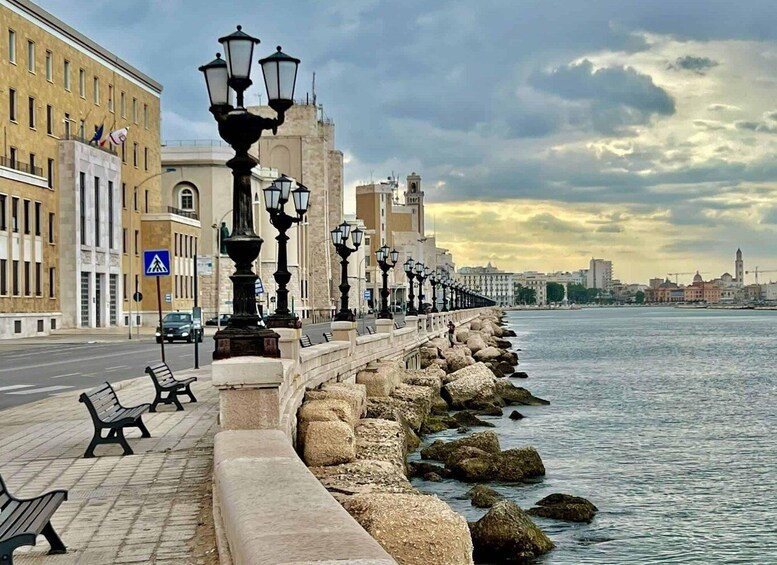 A waterfront promenade with benches, street lamps, and a city skyline in the background. 2
