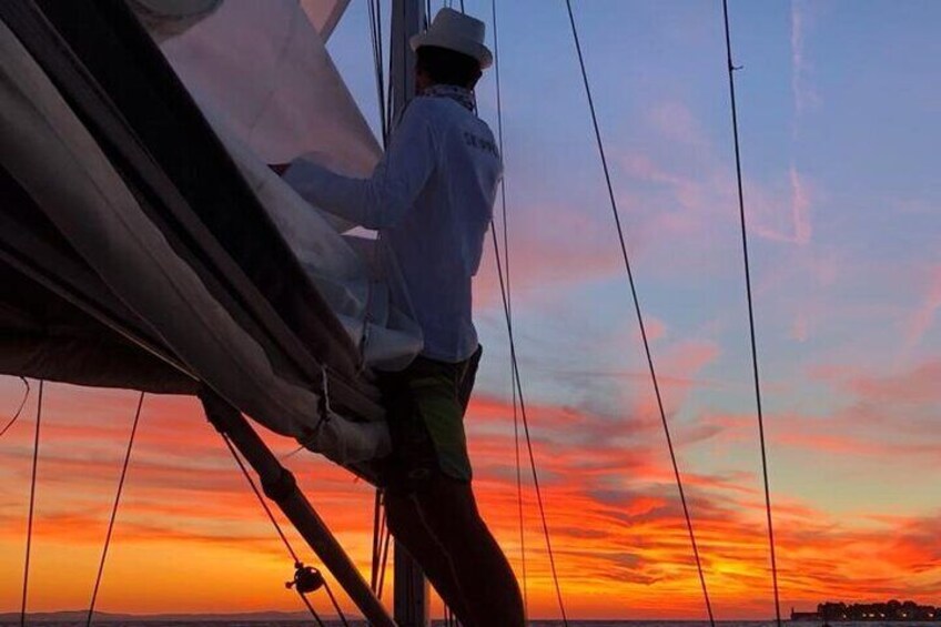 Eine Person segelt bei Sonnenuntergang auf einem Segelboot. 3