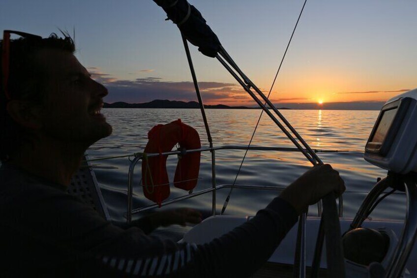 Eine Person steuert bei Sonnenuntergang ein Boot, eine Rettungsboje ist an der Seite befestigt. 5