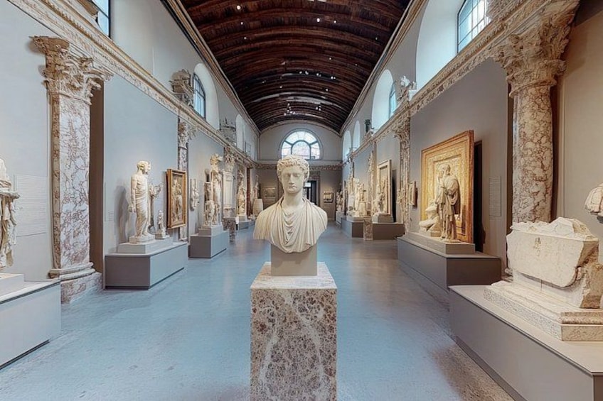 En museums gang med klassiske skulpturer og marmorkolonner. 1