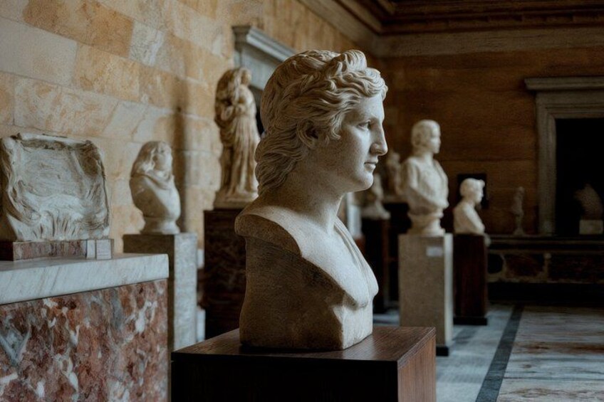 En marmorbuste i et museum med klassiske statuer i baggrunden. 2