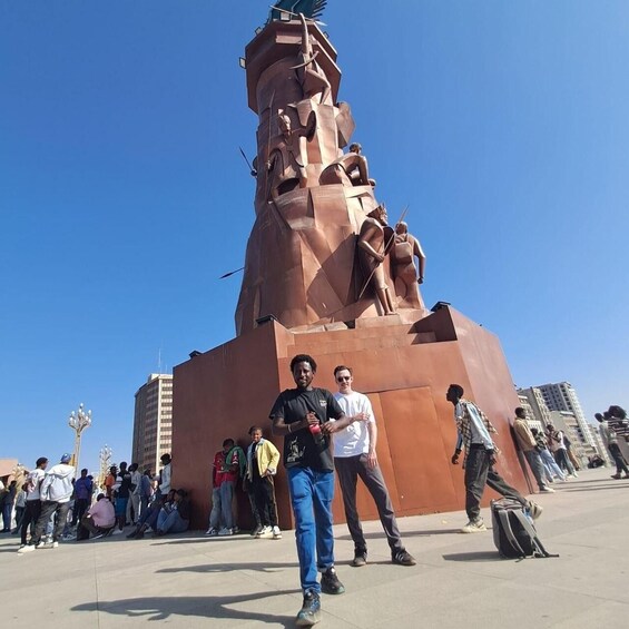 A large bronze statue with multiple figures, surrounded by a crowd of people. 5
