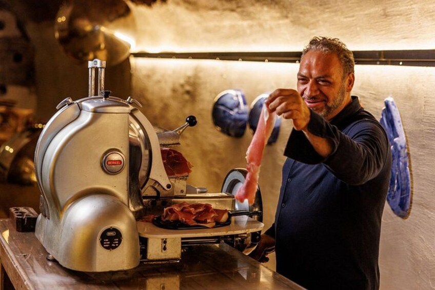 Una persona usando una rebanadora de carne en una cocina. 1