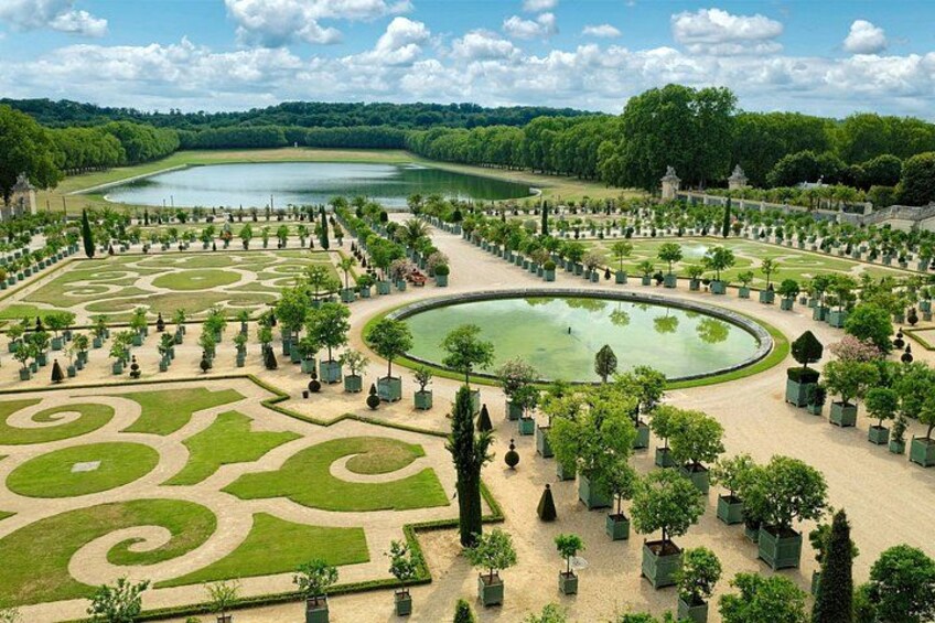 A large, manicured garden with geometric patterns, a central pond, and a variety of trees and shrubs. 5