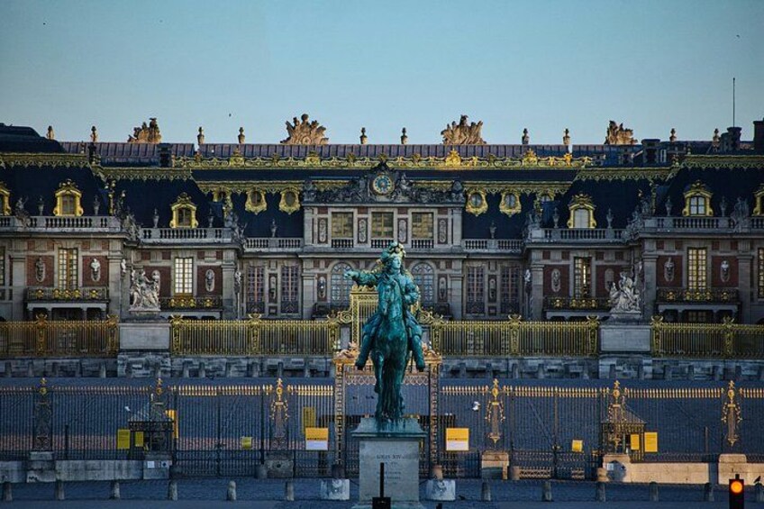 A grand palace with ornate architecture, a prominent statue in the foreground, and a well-maintained garden. 2