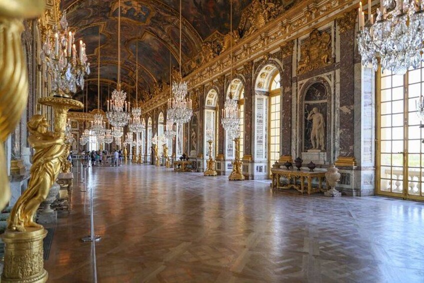 A grand hall with ornate chandeliers, golden statues, and marble columns. 3