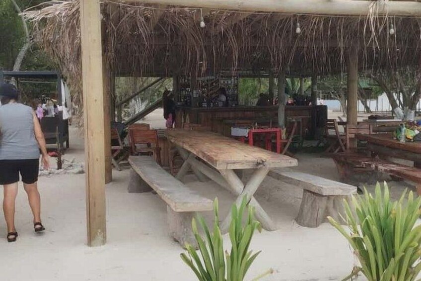 Eine Strandhütte aus Holz mit Bänken und einem Reetdach. 3