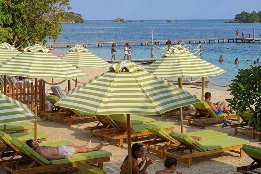 En strand med gule parasoller, liggestole og mennesker, der solbader. 1