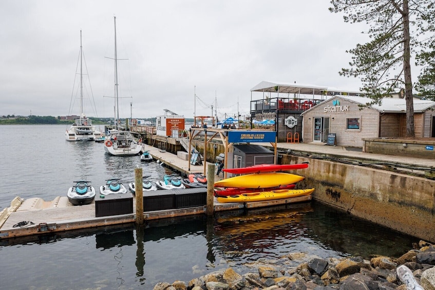 Een jachthaven met boten, kajaks en een houten steiger. 3