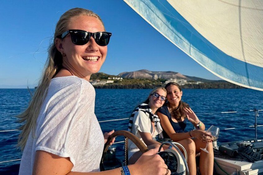 A sailboat with two people on deck, one steering and one sitting. 4