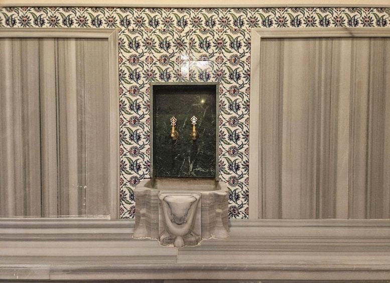 A tiled wall with a decorative pattern and a marble basin. 5