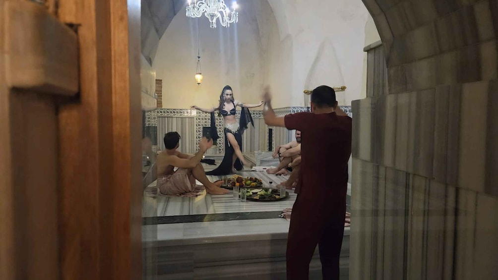 A room with a chandelier, a table with food, and a person in traditional attire. 3