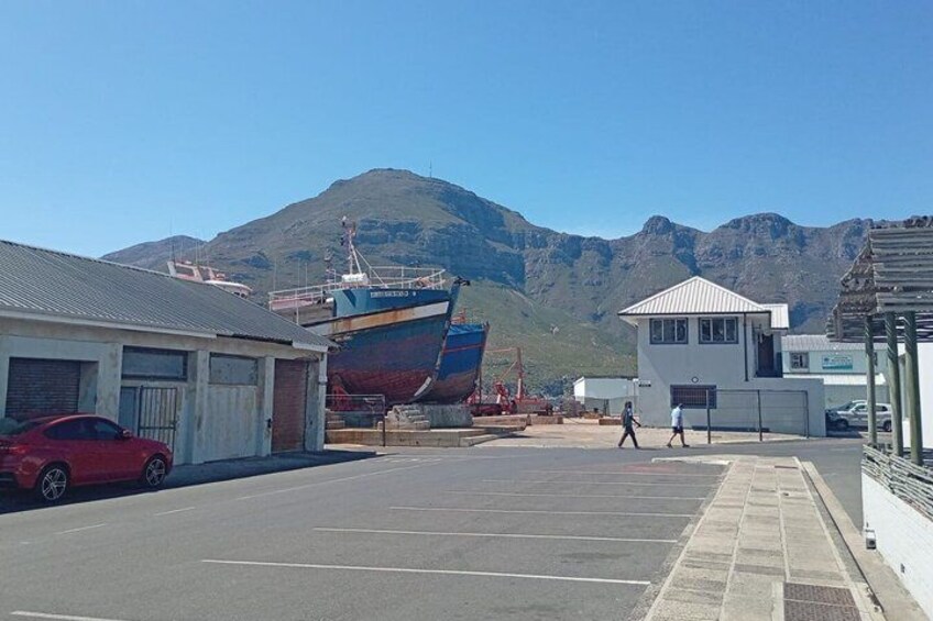 A parking lot with a large boat, a red car, and a mountain in the background. 3
