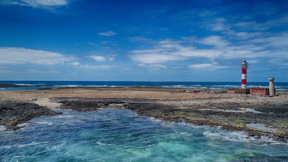 A coastal landscape with a lighthouse, rocky shore, and clear blue waters. 5