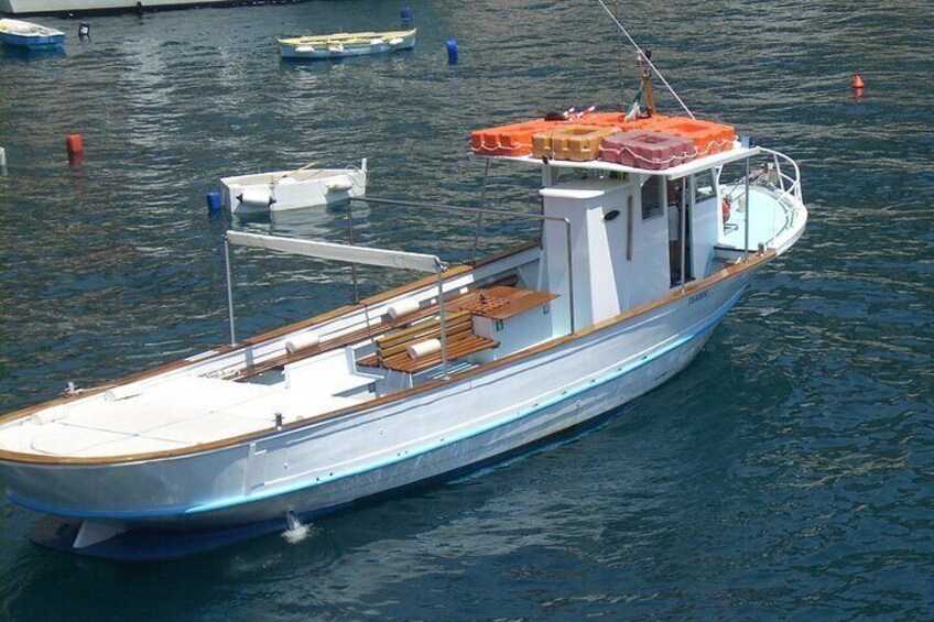 A small, wooden boat docked at a marina with a cabin and a covered area. 3