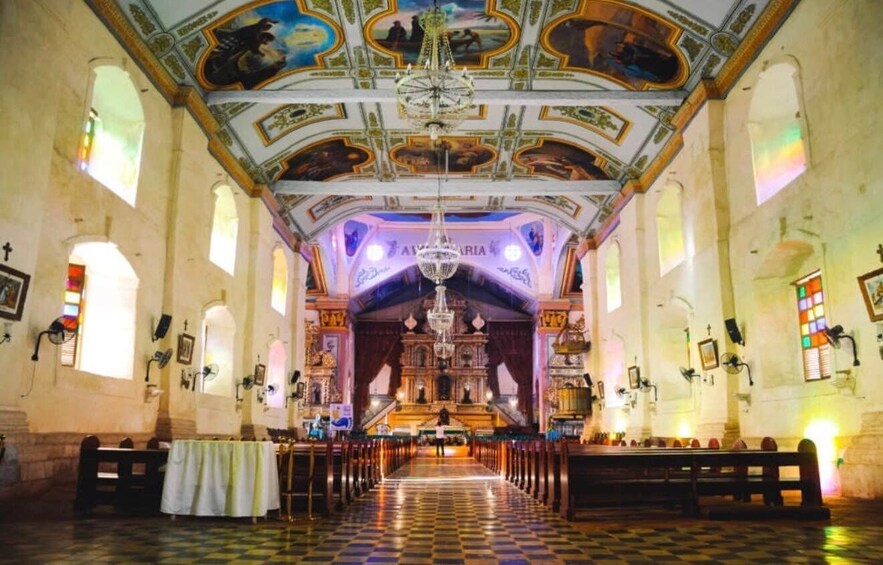 An ornate church interior with a checkered floor, a central altar, and a chandelier. 2