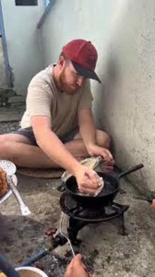 A person cooking outdoors using a portable stove. 2
