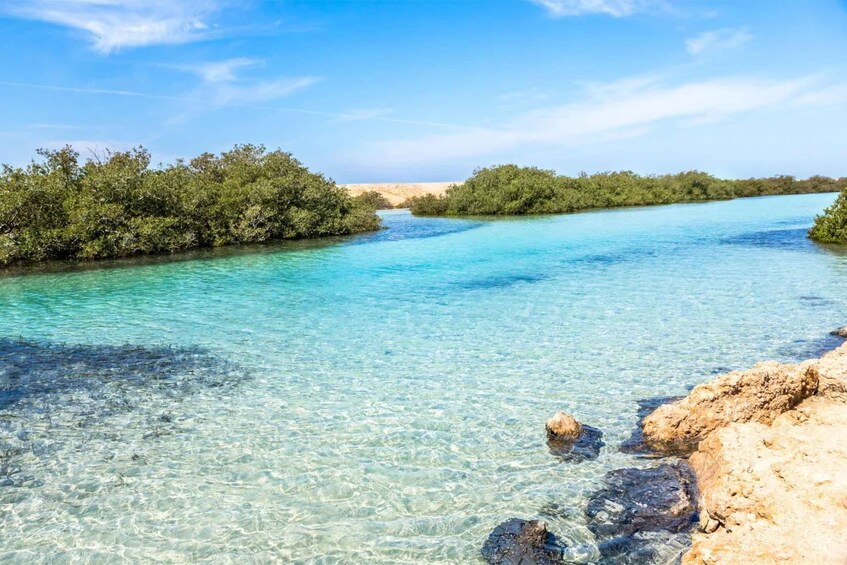 A clear turquoise river bordered by dense greenery and rocky outcrops. 5