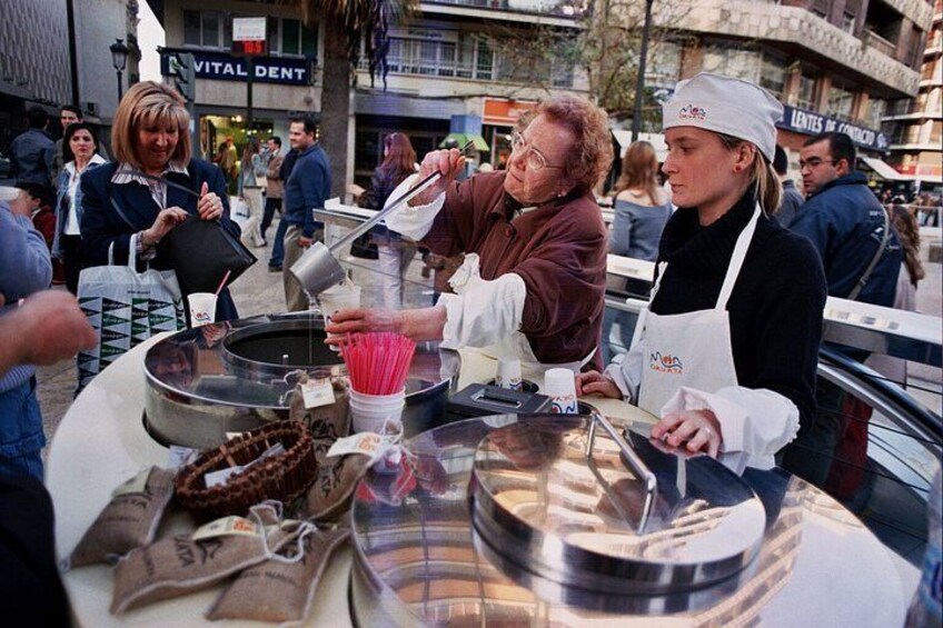 Ein Imbissverkäufer bereitet Essen an einem Stand zu, im Hintergrund eine Menschenmenge. 4