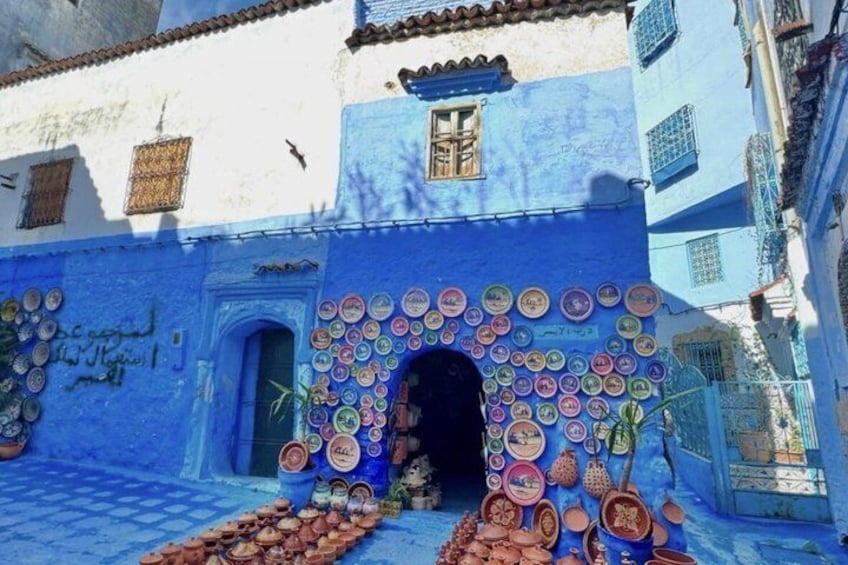 A building with a blue facade and a door adorned with colorful plates. 3