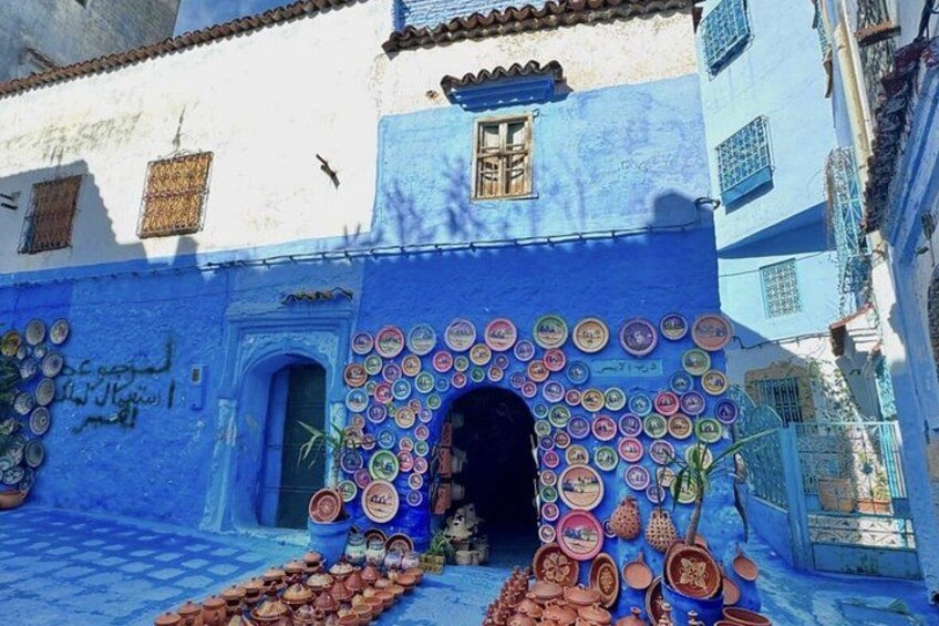 A building with a blue facade and a door decorated with colorful plates. 3