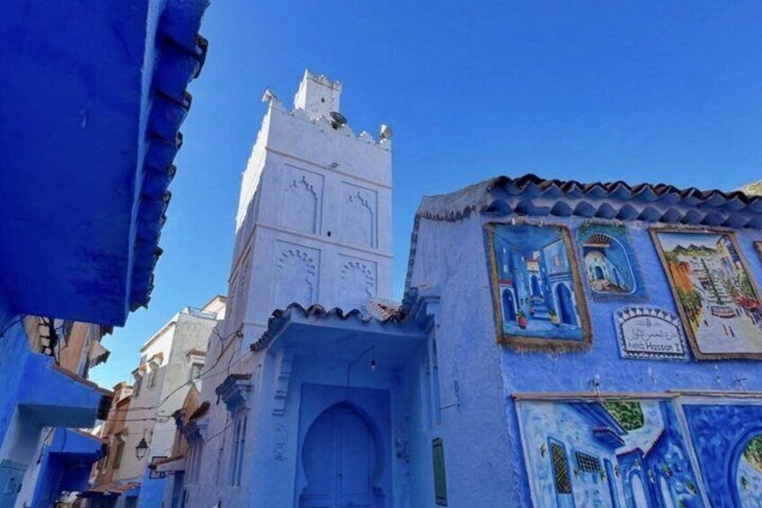A blue-painted building with a clock tower and decorative murals. 1