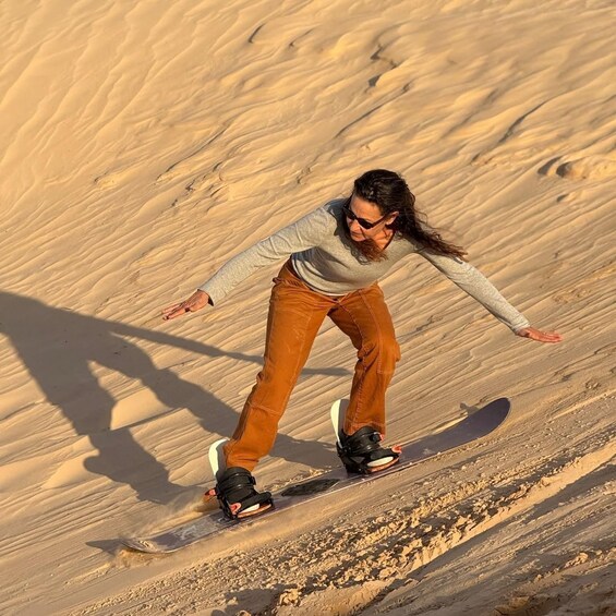 A person snowboarding down a sandy slope. 1