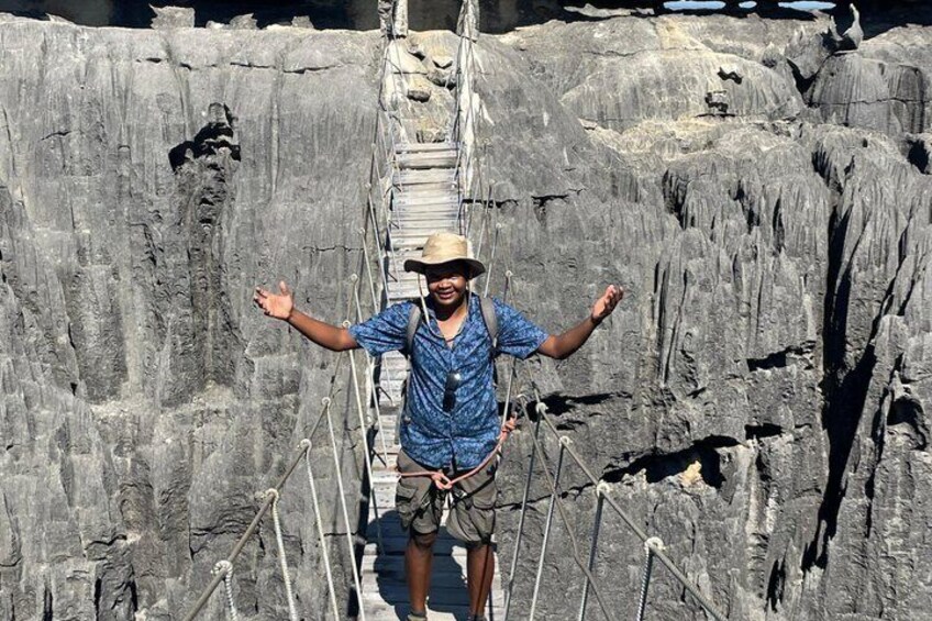 A person standing on a rope bridge over a rocky cliff. 3
