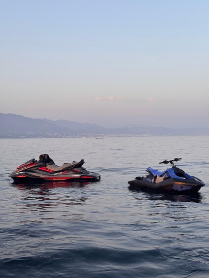 Two snowmobiles on a calm lake with mountains in the background. 2