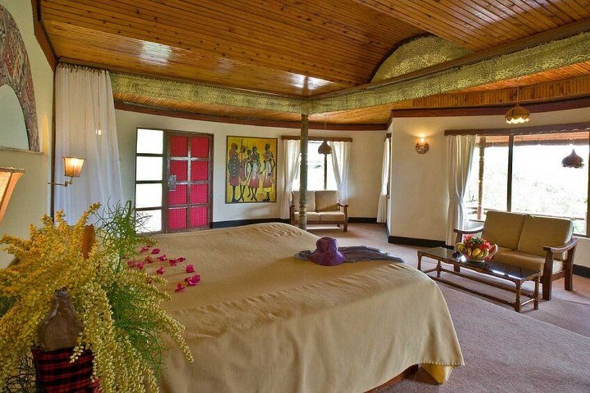 A large bed with a beige bedspread, a wooden ceiling, and a painting on the wall. 5