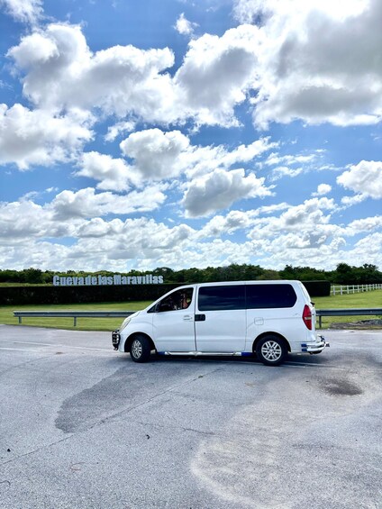 A white van parked on a road with a clear sky and clouds. 1