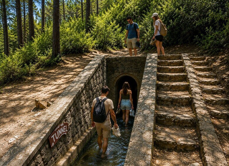 A stone tunnel with a sign reading 'TUNNEL' and a set of stone steps leading up to it. 2