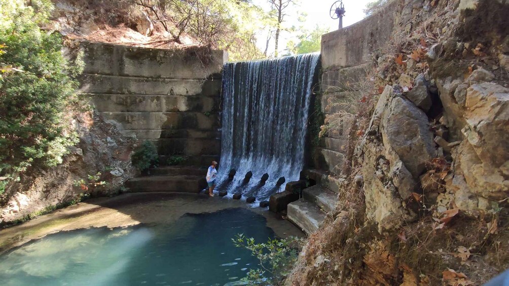 A waterfall cascading into a pool surrounded by stone walls and vegetation. 4