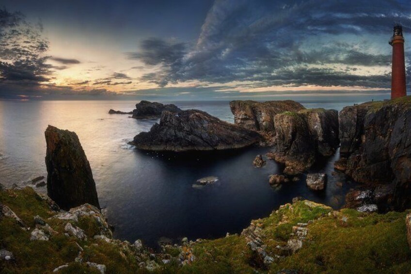 A coastal landscape with a lighthouse, rocky outcrops, and calm sea. 3