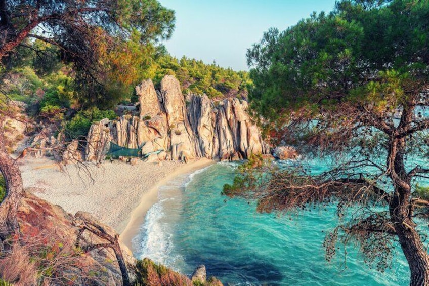 Paesaggio costiero con spiaggia sabbiosa, acque turchesi cristalline e scogliere rocciose. 1