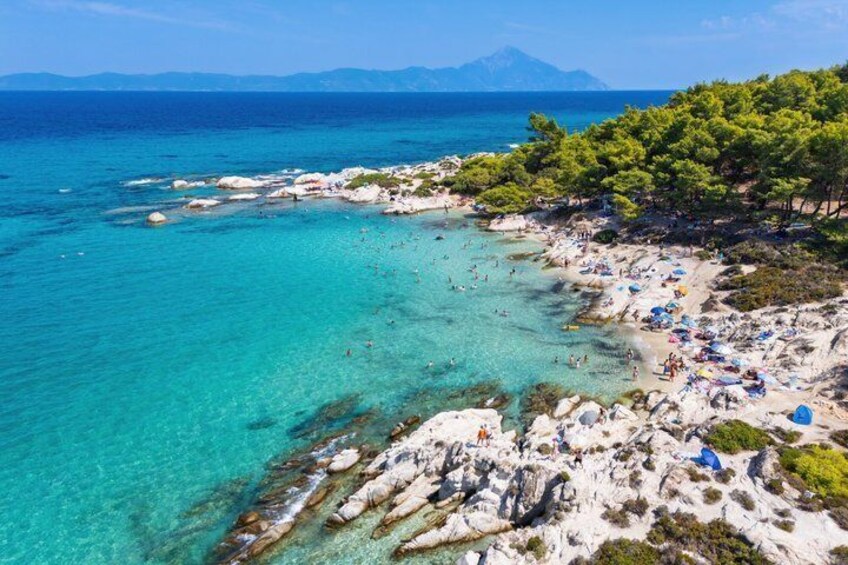 Una spiaggia costiera con acque cristalline color turchese, rocce e una vegetazione rigogliosa. 3