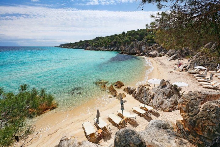 Una spiaggia con acque cristalline turchesi, una riva sabbiosa e affioramenti rocciosi. 2