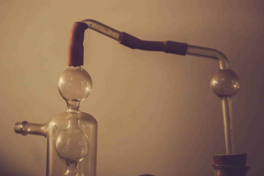 A glass distillation apparatus with a curved metal pipe and a spherical glass bulb. 3