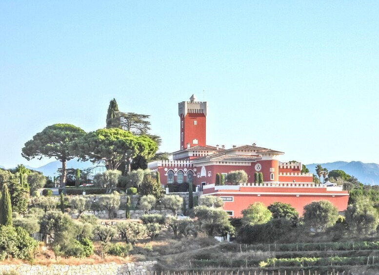 A red building with a tower, surrounded by trees and a clear sky. 1