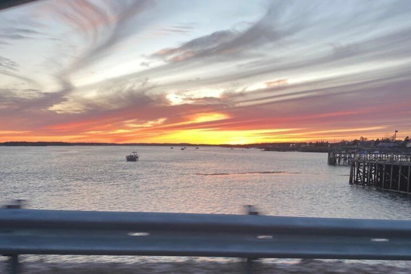 Un atardecer sobre una superficie acuática tranquila con un muelle que se adentra en el agua. 1