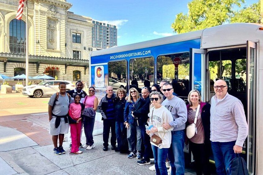 Eine Gruppe von Menschen steht vor einem blauen Bus mit der Aufschrift 'DiscoverDenverTours.com'. 5