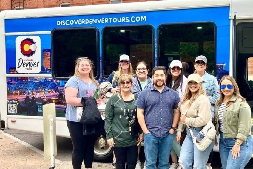 Un groupe de personnes se tient devant un autobus sur lequel on peut lire : « Découvrez Denver avec nos visites guidées ». 5