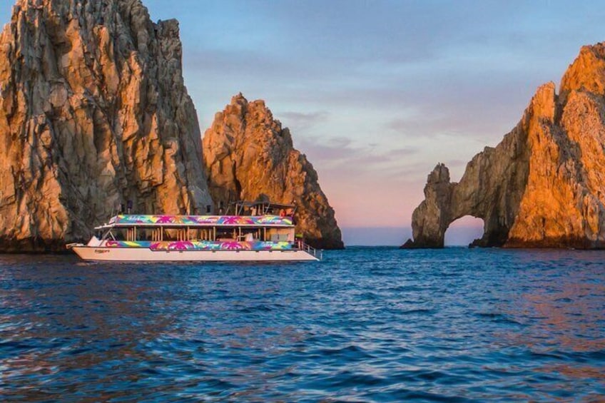 Un bateau, décoré de parasols aux couleurs vives, est amarré dans une crique bordée de formations rocheuses. 1