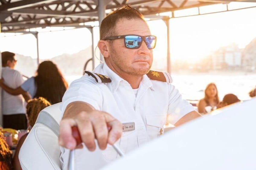Une personne vêtue d’un uniforme blanc, portant une étiquette avec son nom, et qui désigne quelque chose. 2