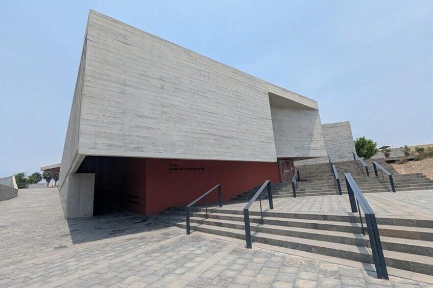Een modern gebouw met een schuin dak, een trap naar de ingang en een geplaveid pad. 5