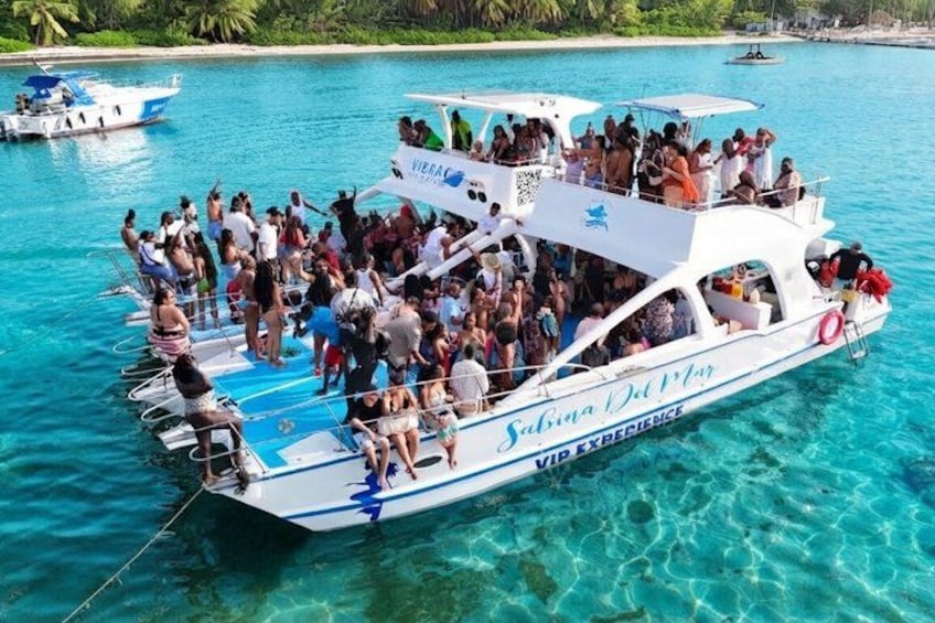A boat with 'VIP Experience' written on it, filled with people, floating on clear blue water. 4